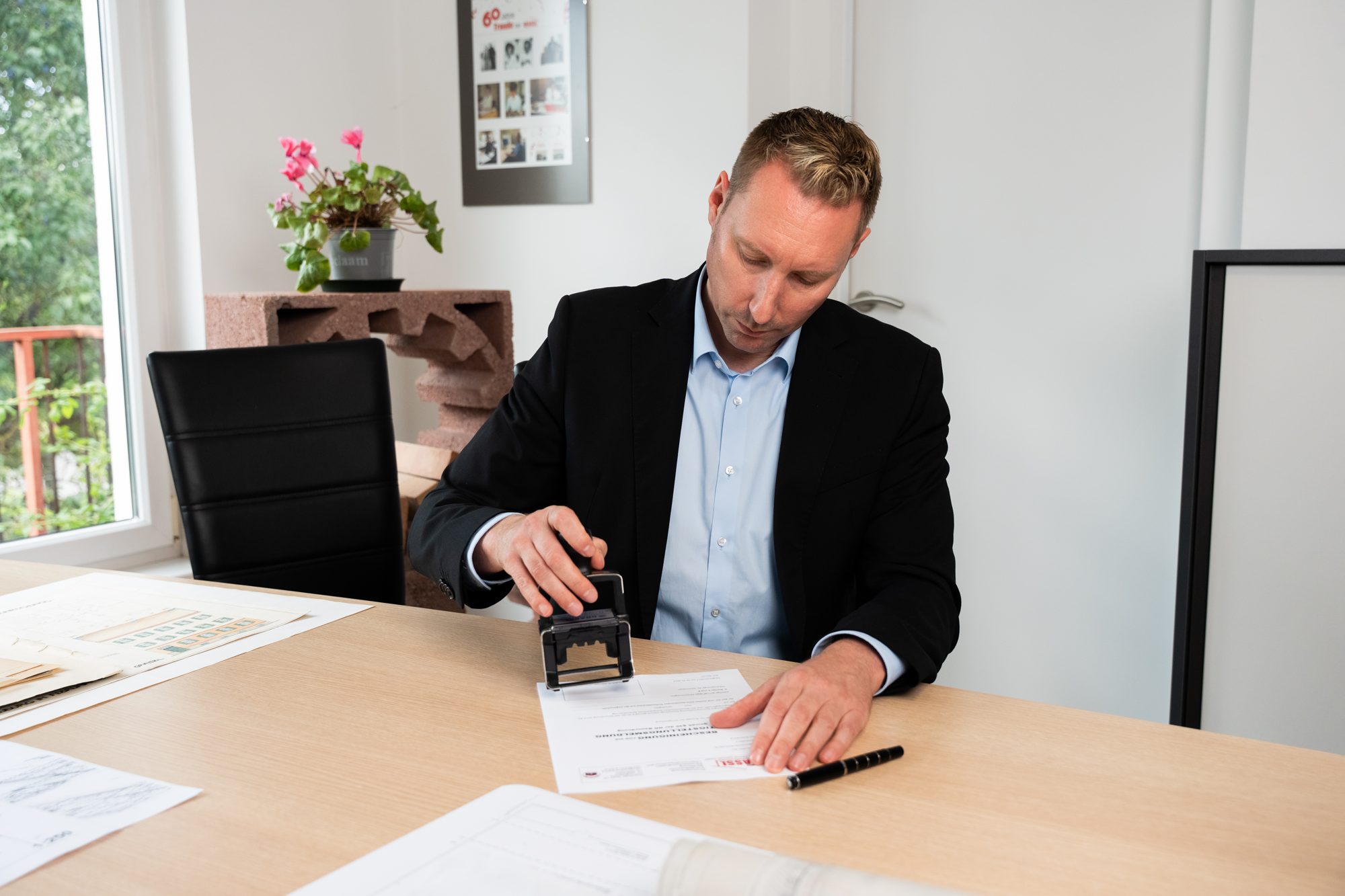 Franz Grassl stempelt im Büro eine Bescheinigung zur Fertigstellung