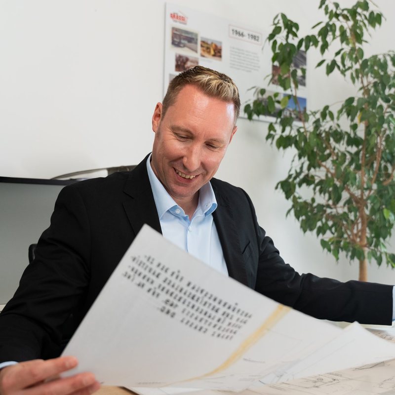 DI Franz Grassl, Baumeister und Geschäftsführer der Dipl.-Ing. Franz Grassl GmbH, liest lächelnd einen Plan